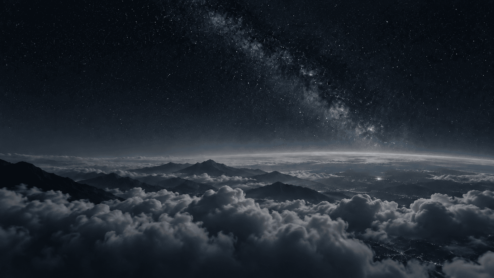 Night sky over a layer of clouds and distant mountains