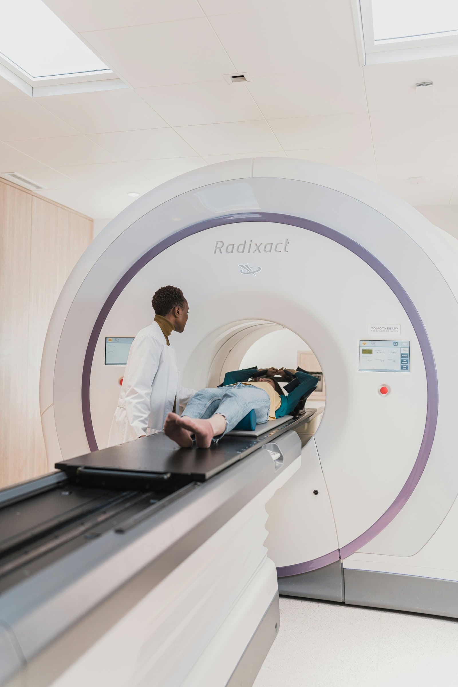 A clinician preparing a patient on the table of a radiation therapy system